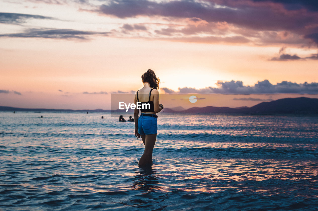 Rear view of woman at beach during sunset