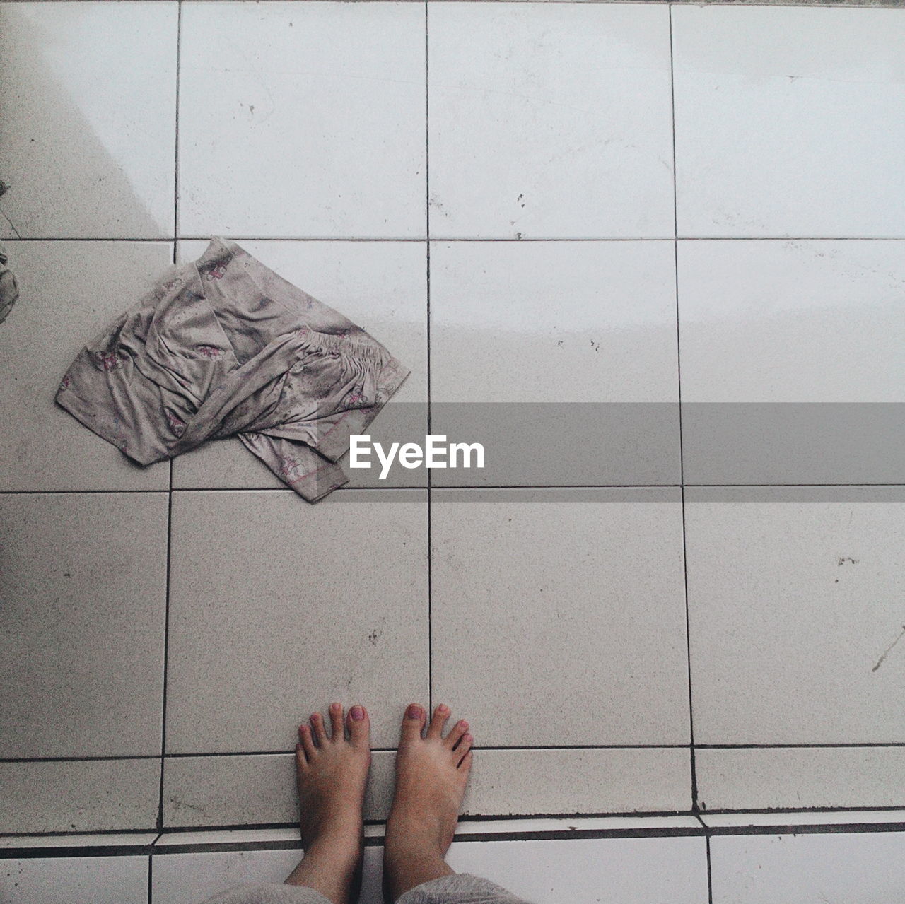 Low section of woman standing by fabric on tiled floor