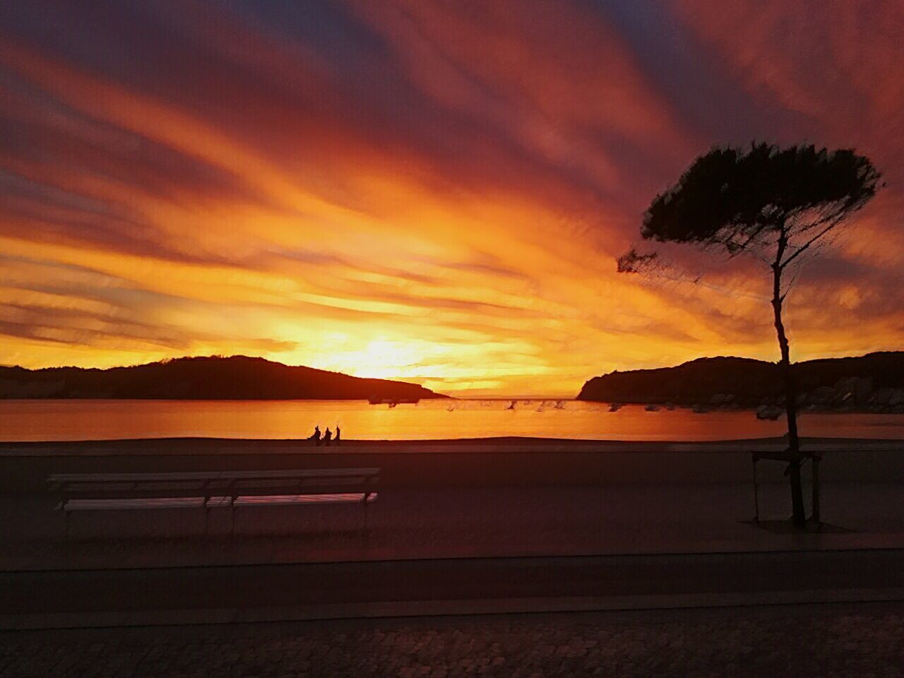 Scenic view of beach against cloudy sky during sunset