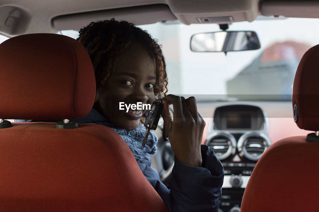 Portrait of smiling woman holding car key sitting in car