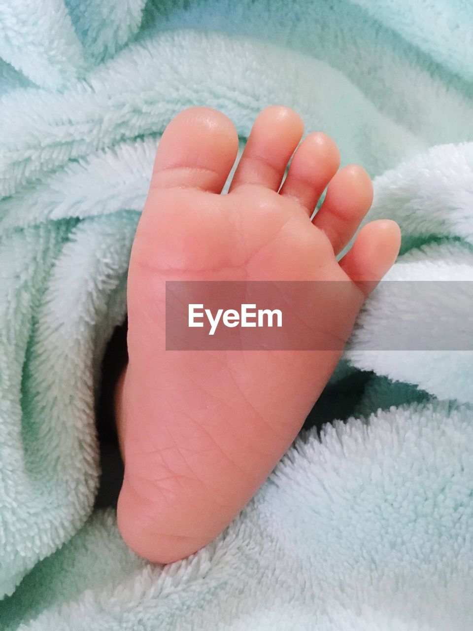Close-up of baby foot on bed