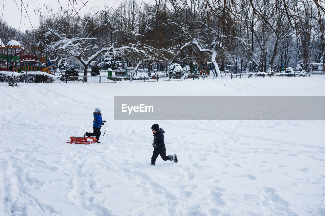 PEOPLE PLAYING ON SNOW COVERED FIELD