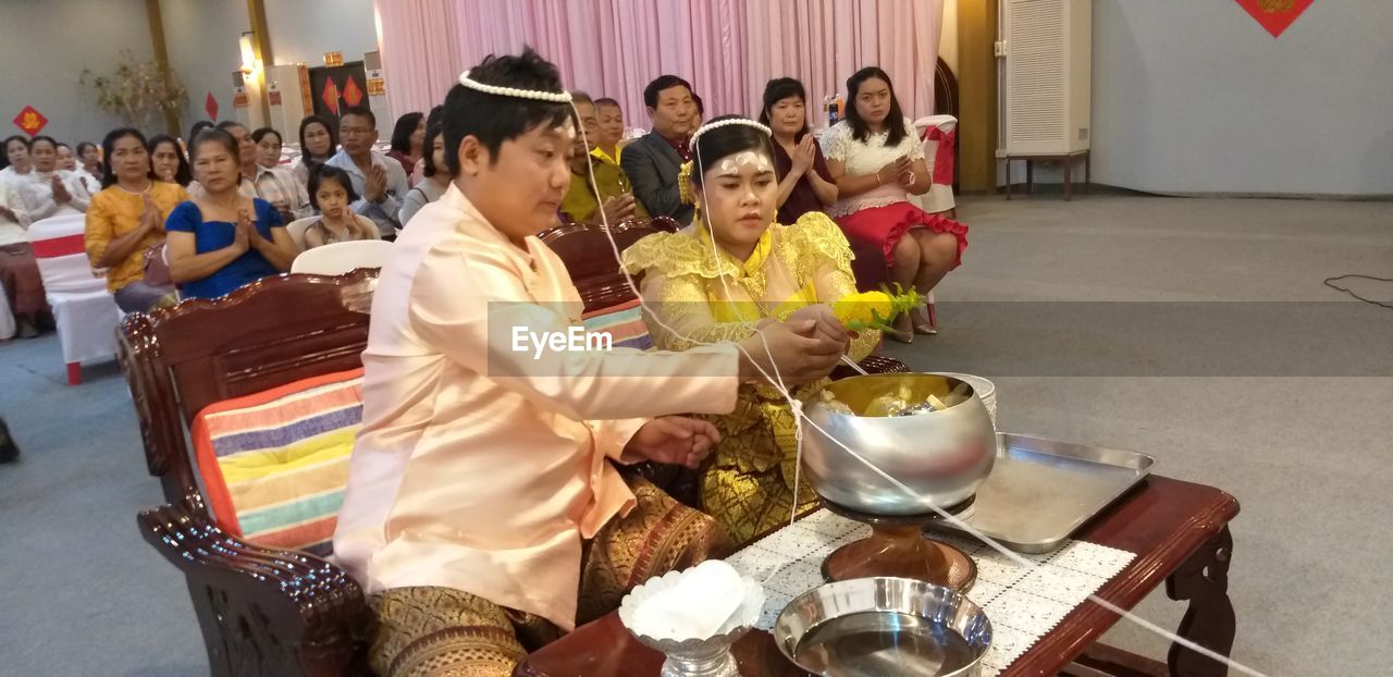 GROUP OF PEOPLE SITTING IN TRADITIONAL CLOTHING