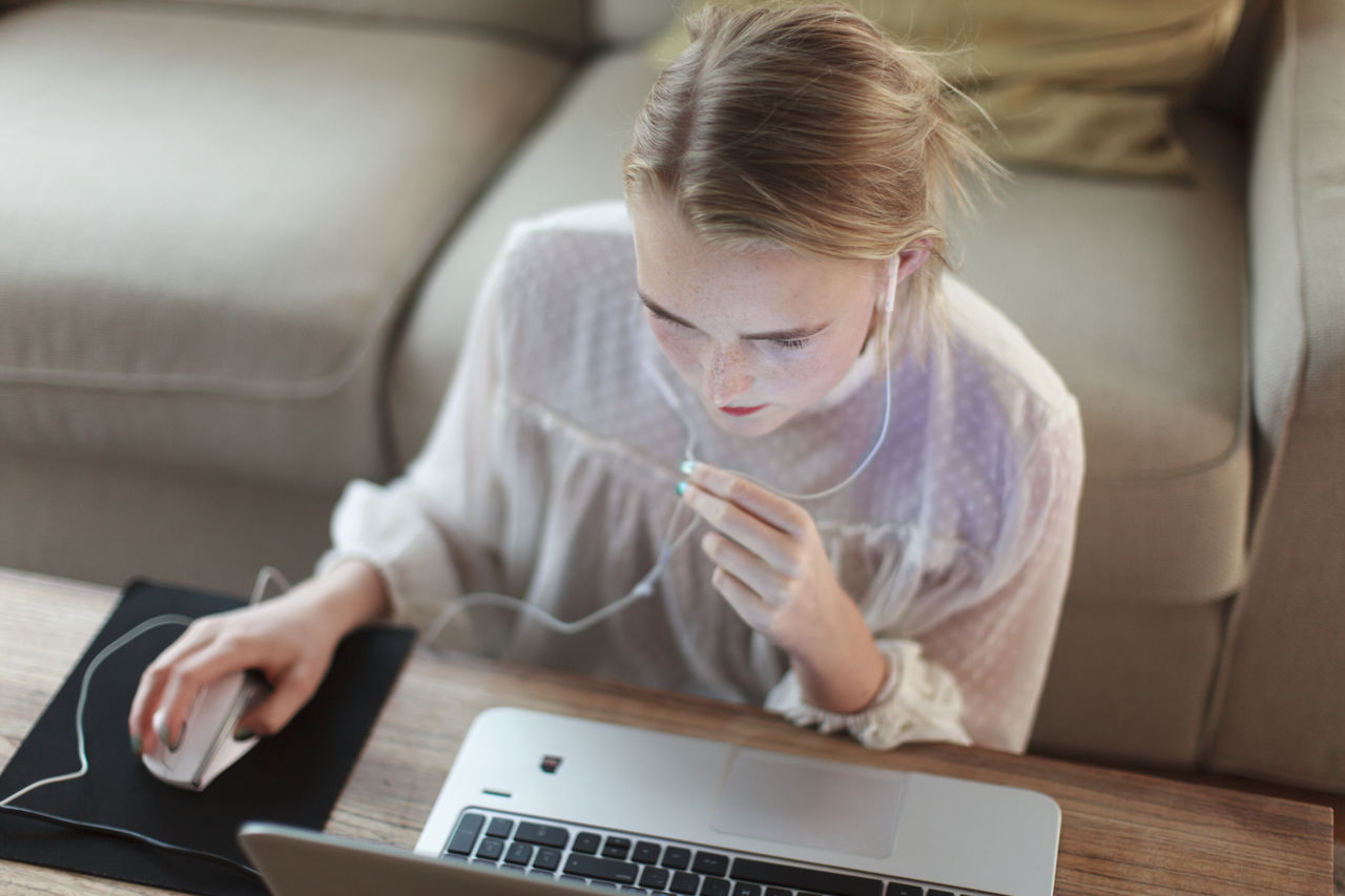 Teenage girl using laptop in living room