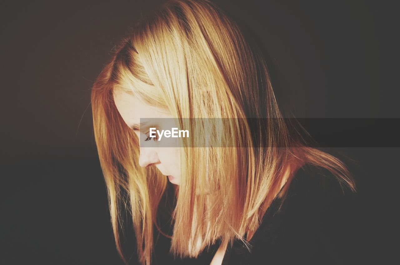 Close-up of thoughtful woman against black background