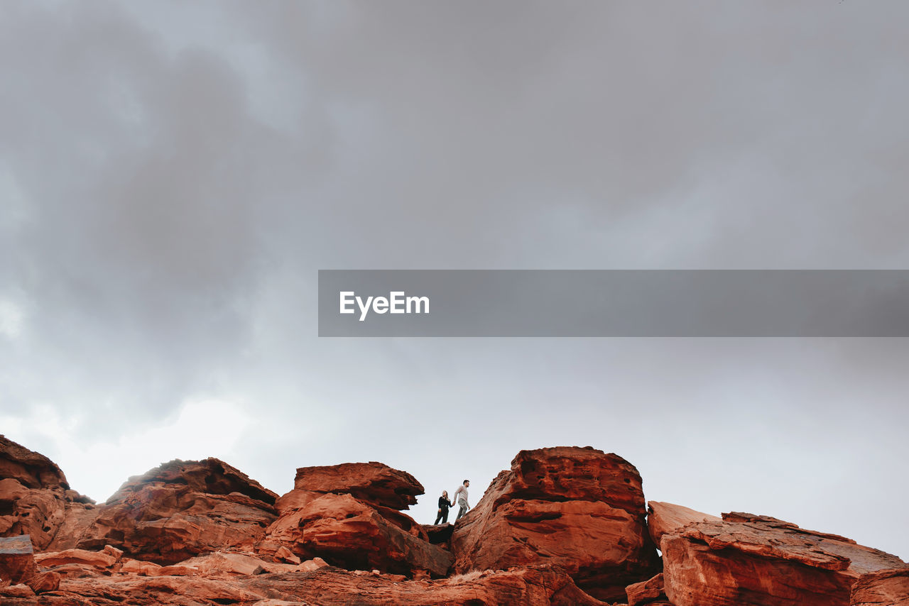 From below of unrecognizable traveling couple holding hands and walking on rocks in wadi rum during holiday in jordan