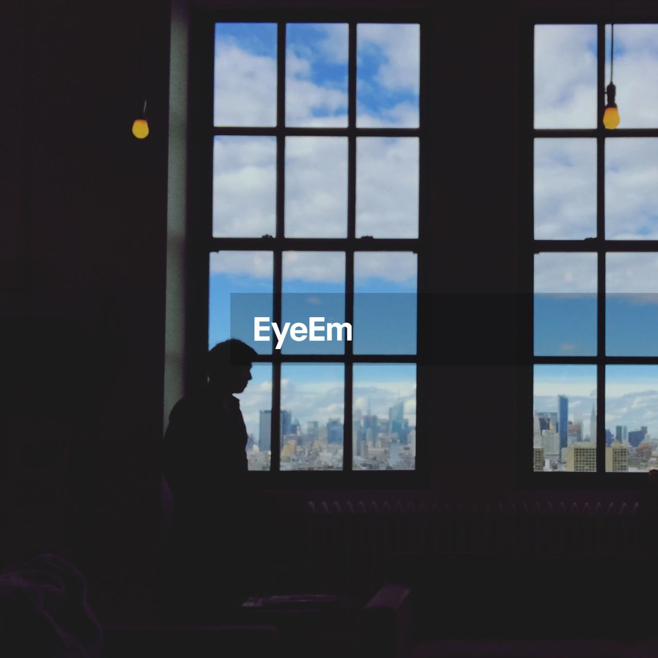SILHOUETTE OF MAN LOOKING THROUGH WINDOW AT HOME