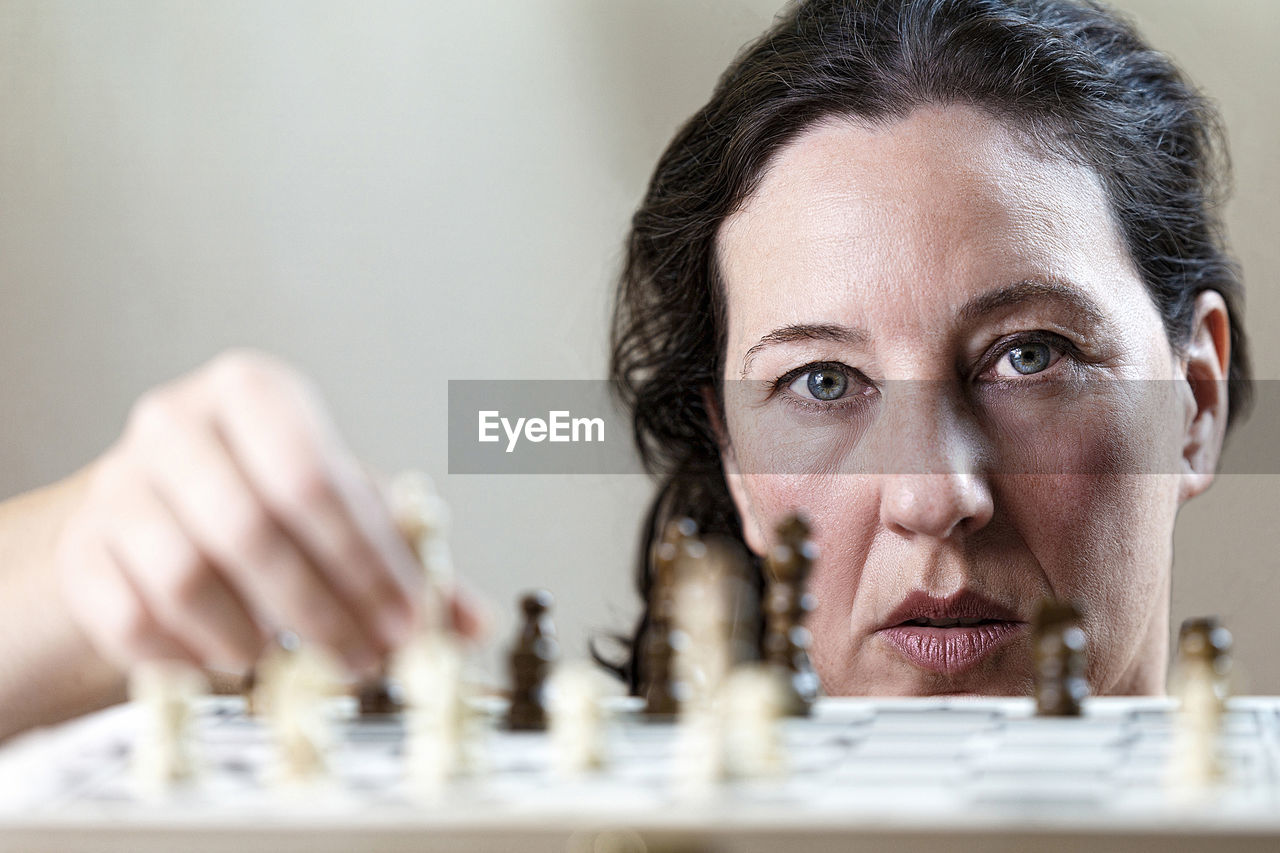 Close-up portrait of woman playing chess at home