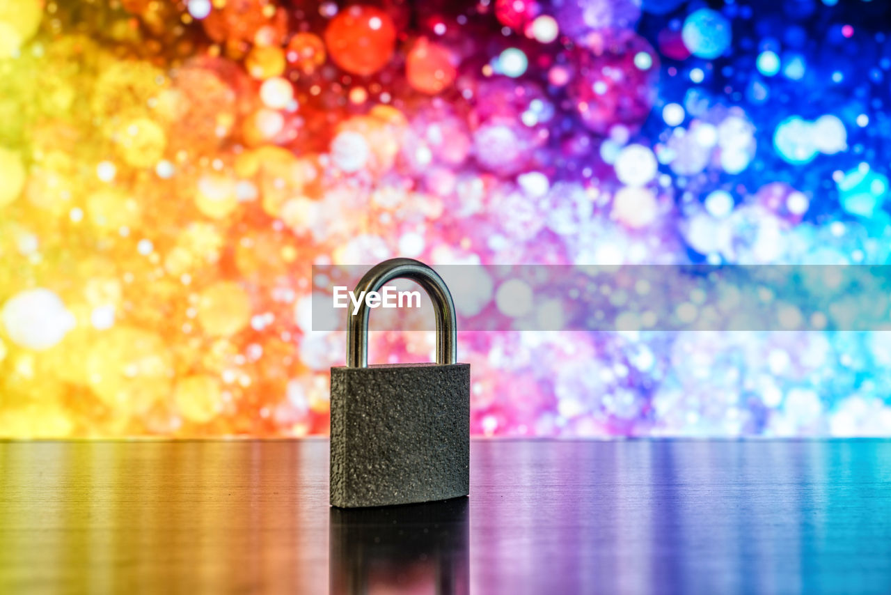 Close-up of padlock on table against colorful illuminated lights