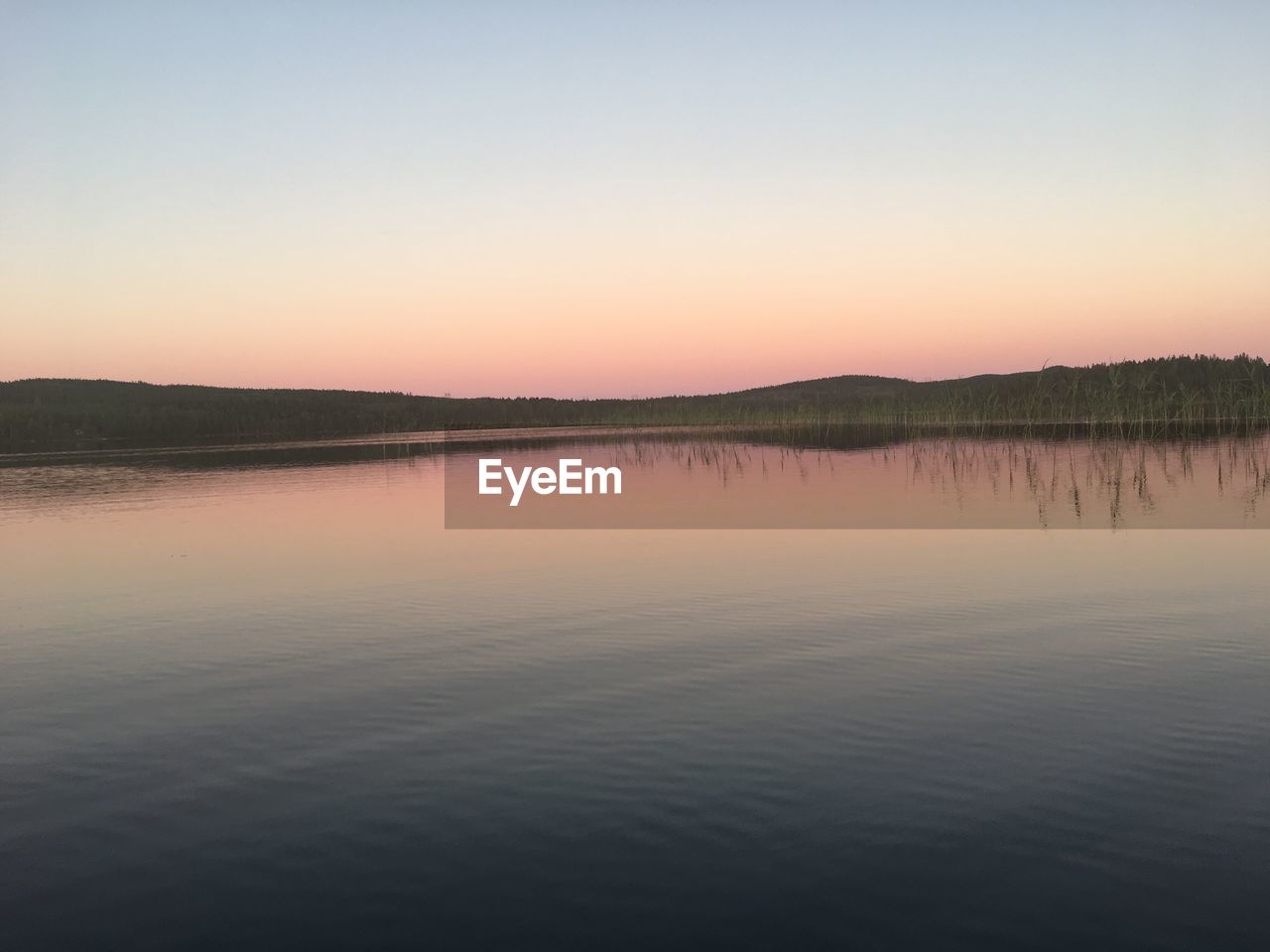 Scenic view of lake against clear sky during sunset