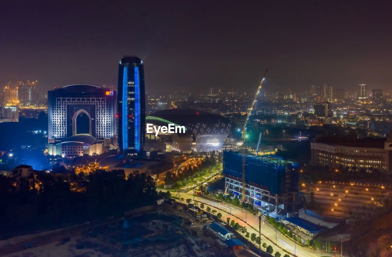 Illuminated buildings in city against sky at night