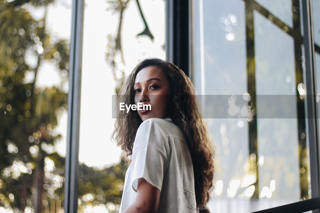 Portrait of beautiful woman by glass window