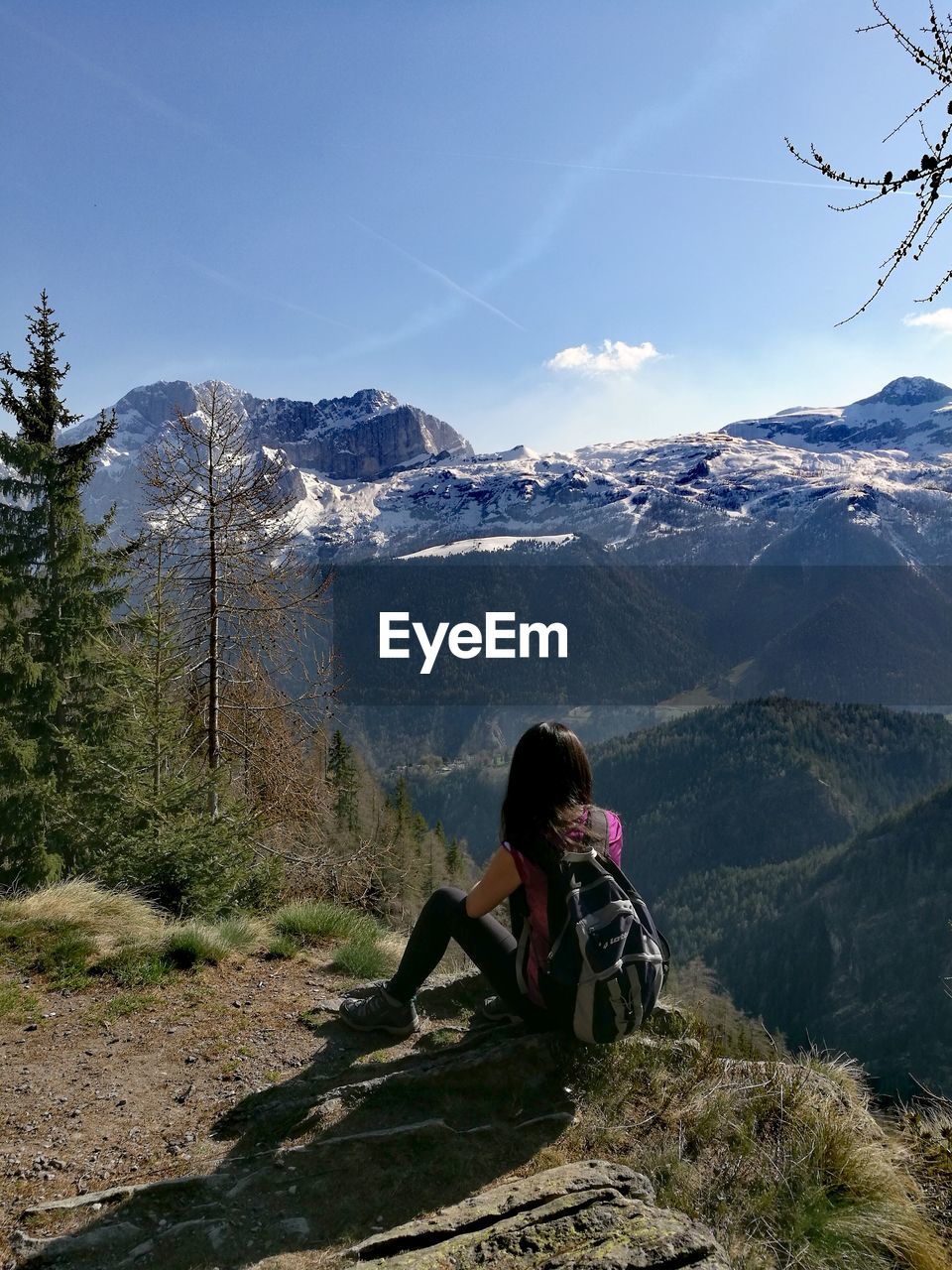 Rear view of backpacker looking at mountains against sky during winter