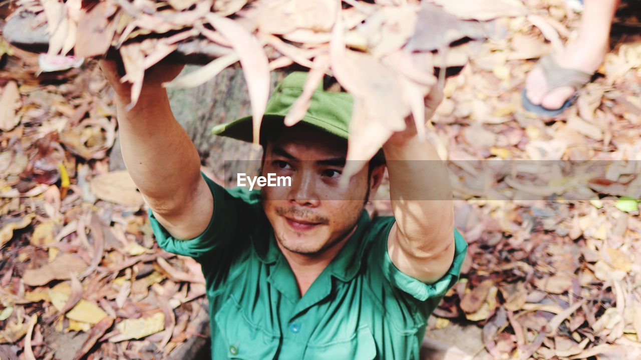 PORTRAIT OF YOUNG MAN WITH AUTUMN LEAVES IN PARK