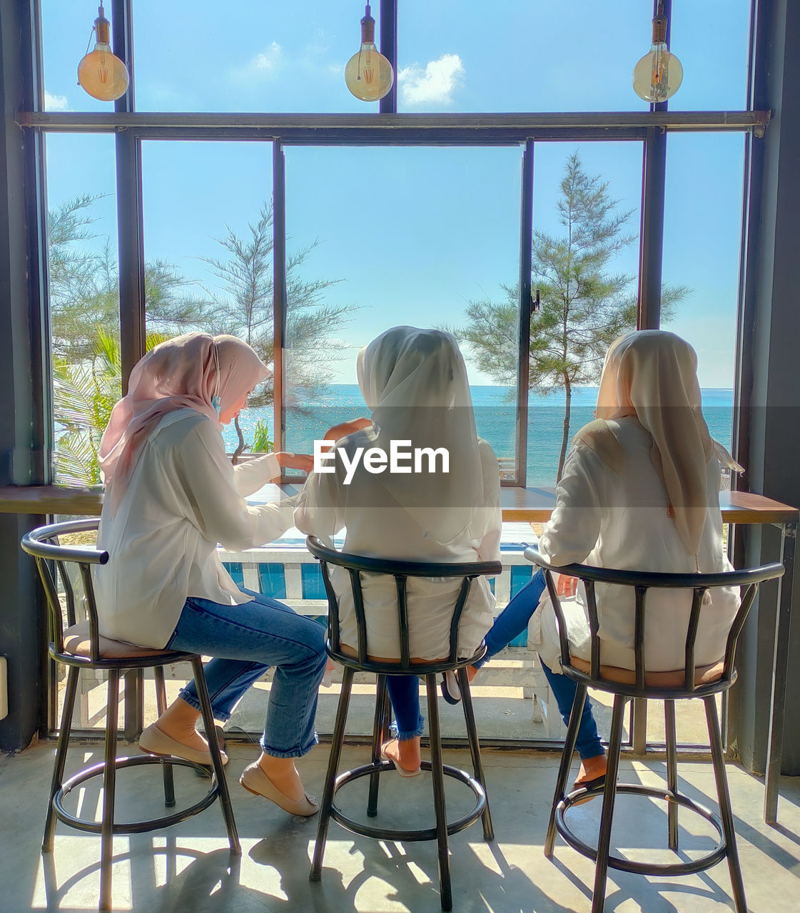 REAR VIEW OF PEOPLE SITTING ON TABLE IN ROOM