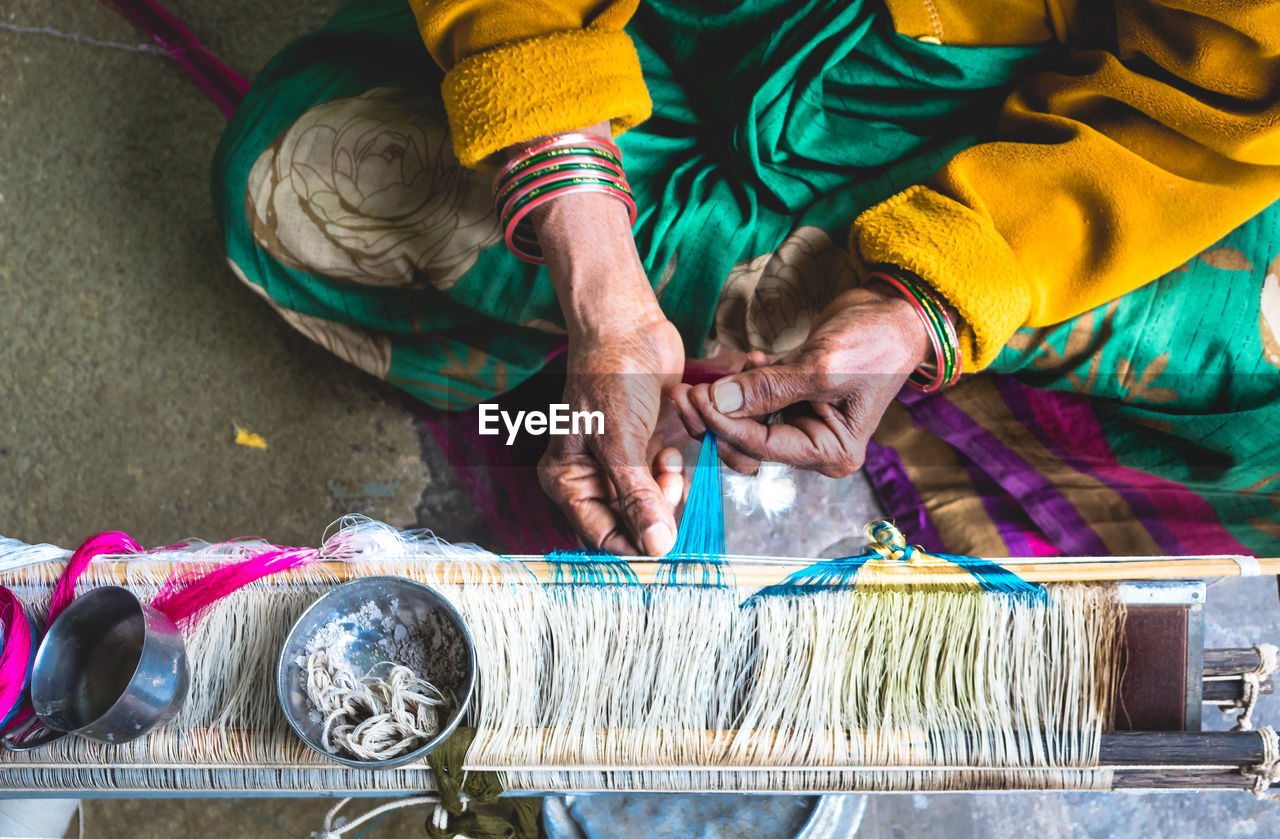 High angle view of woman working on loom in factory