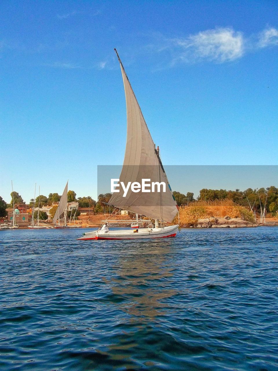 Sailboat sailing on sea against blue sky