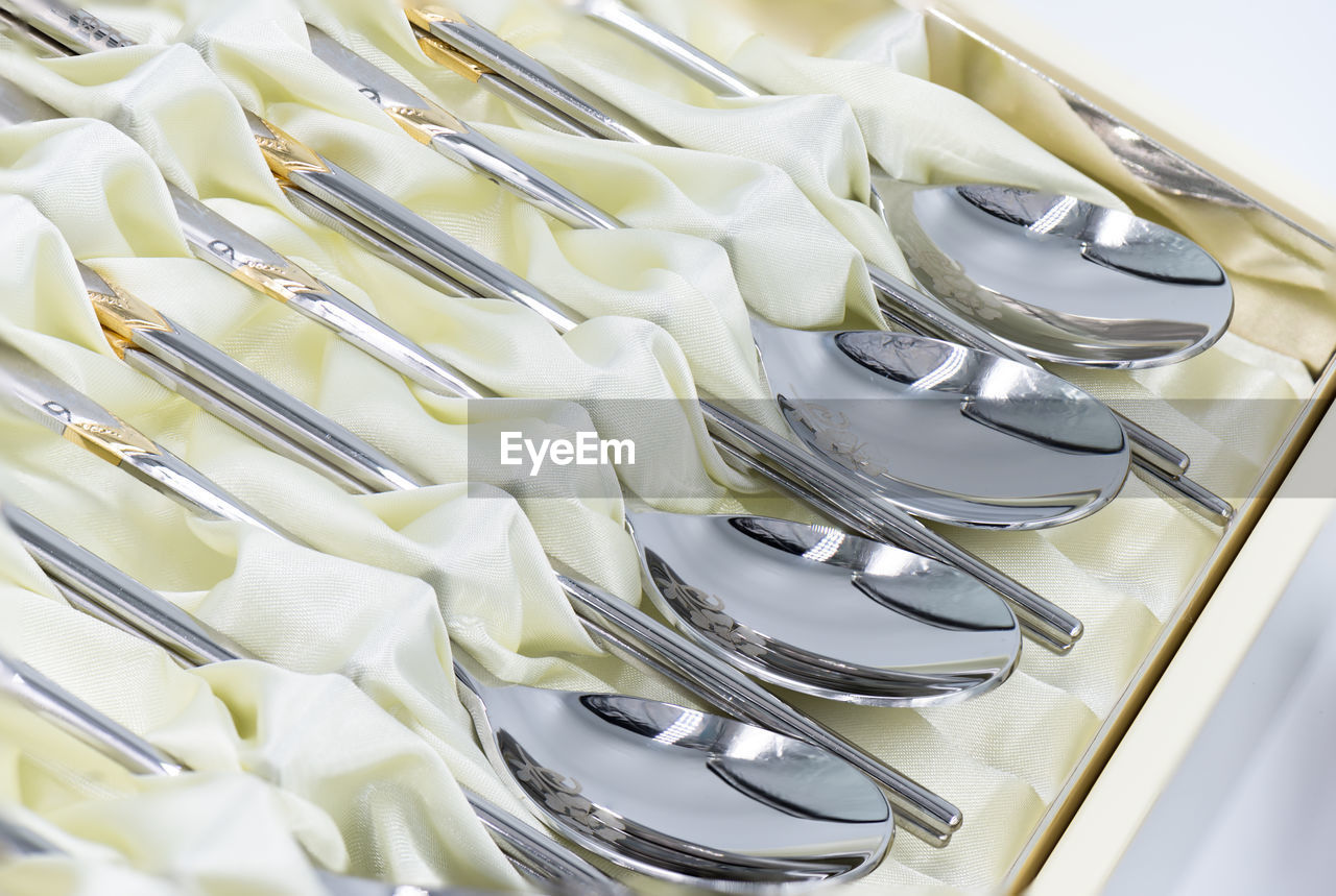 High angle view of spoons with fabric arranged in box on table