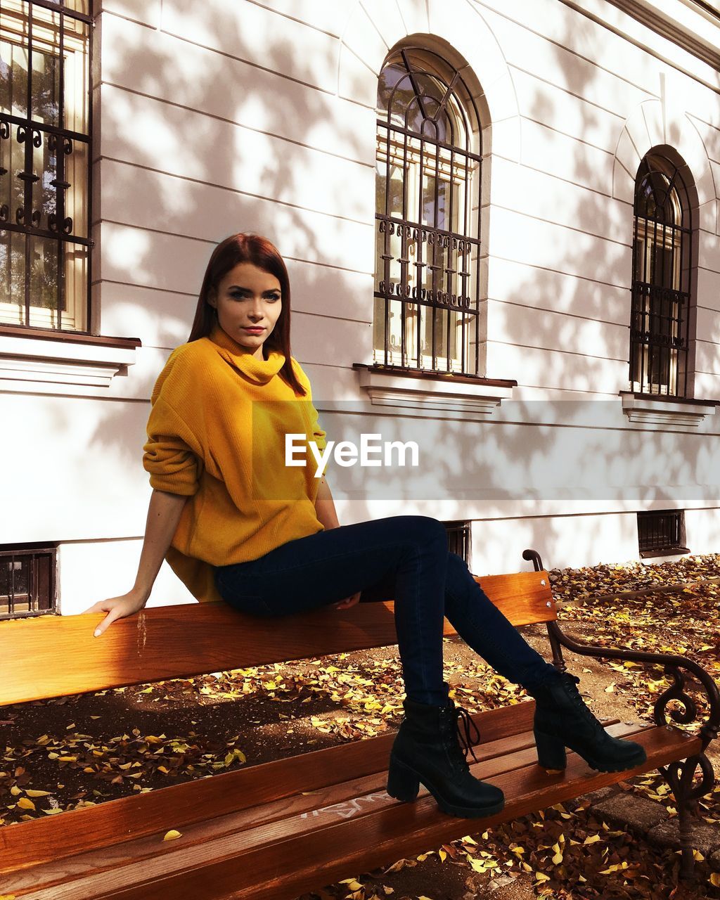 Young woman sitting on chair against building