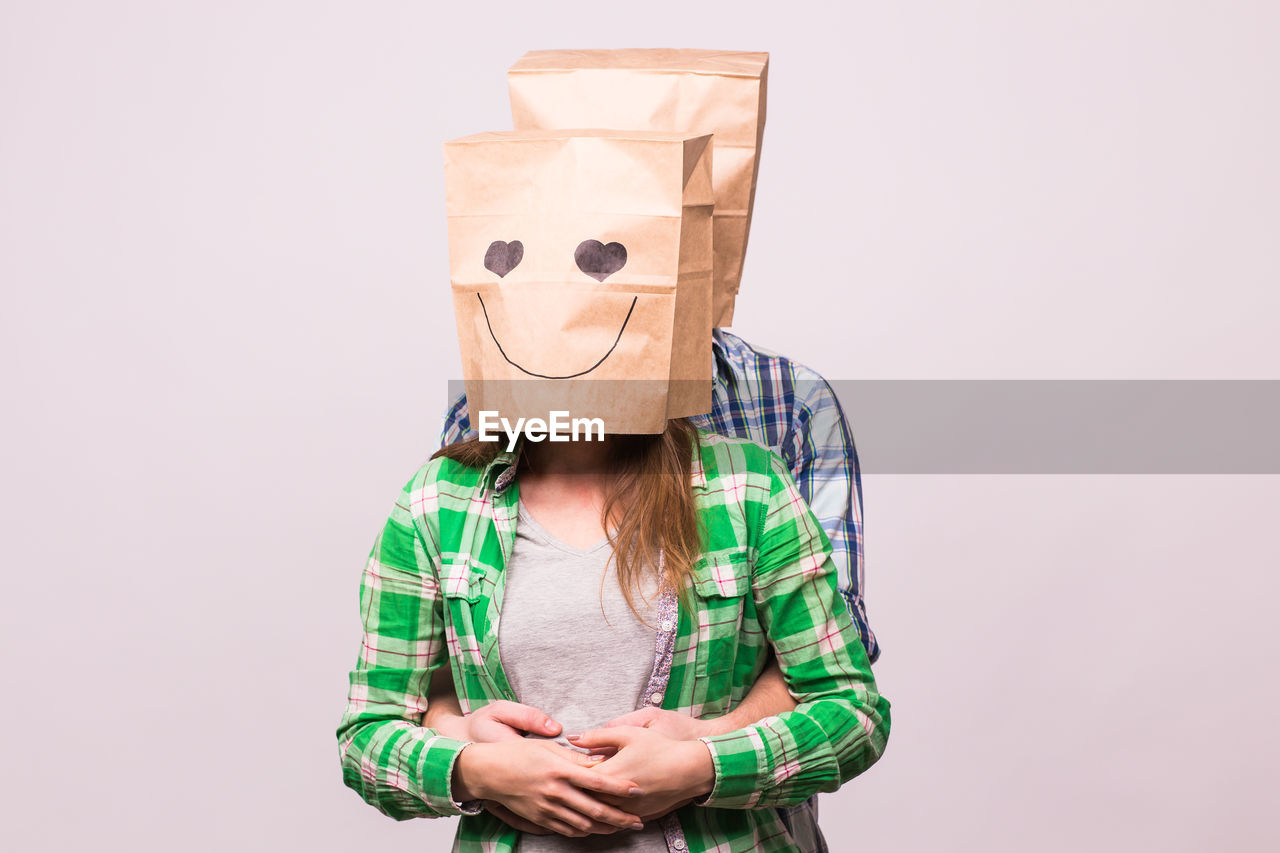 FULL LENGTH PORTRAIT OF A PERSON HIDING FACE AGAINST WHITE BACKGROUND