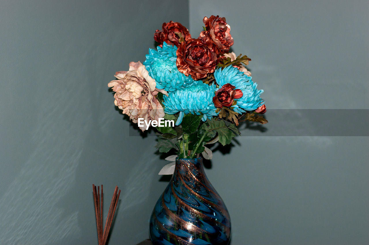 Close-up of flower vase on table against wall