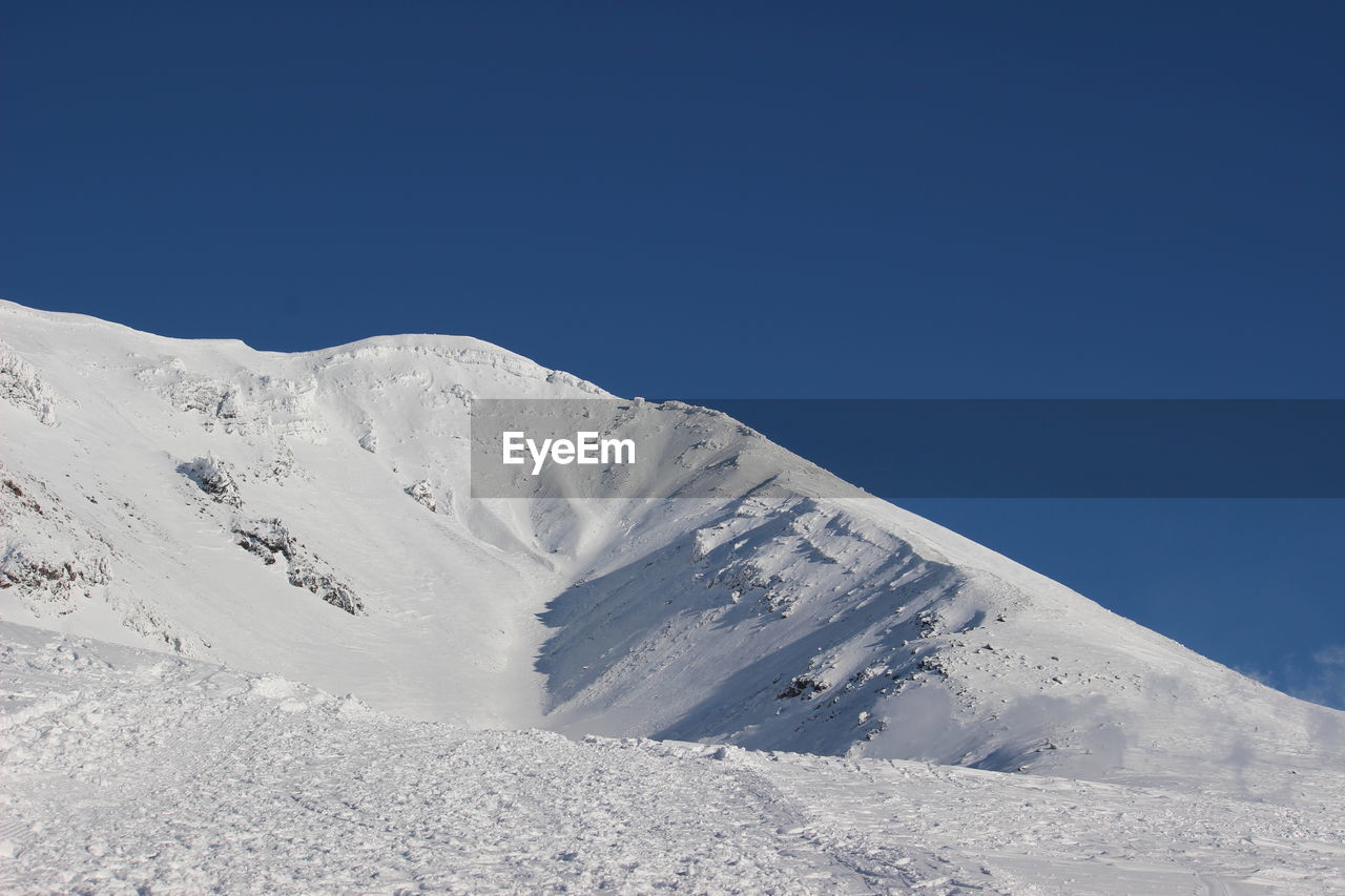 Scenic view of snowcapped mountains against clear blue sky