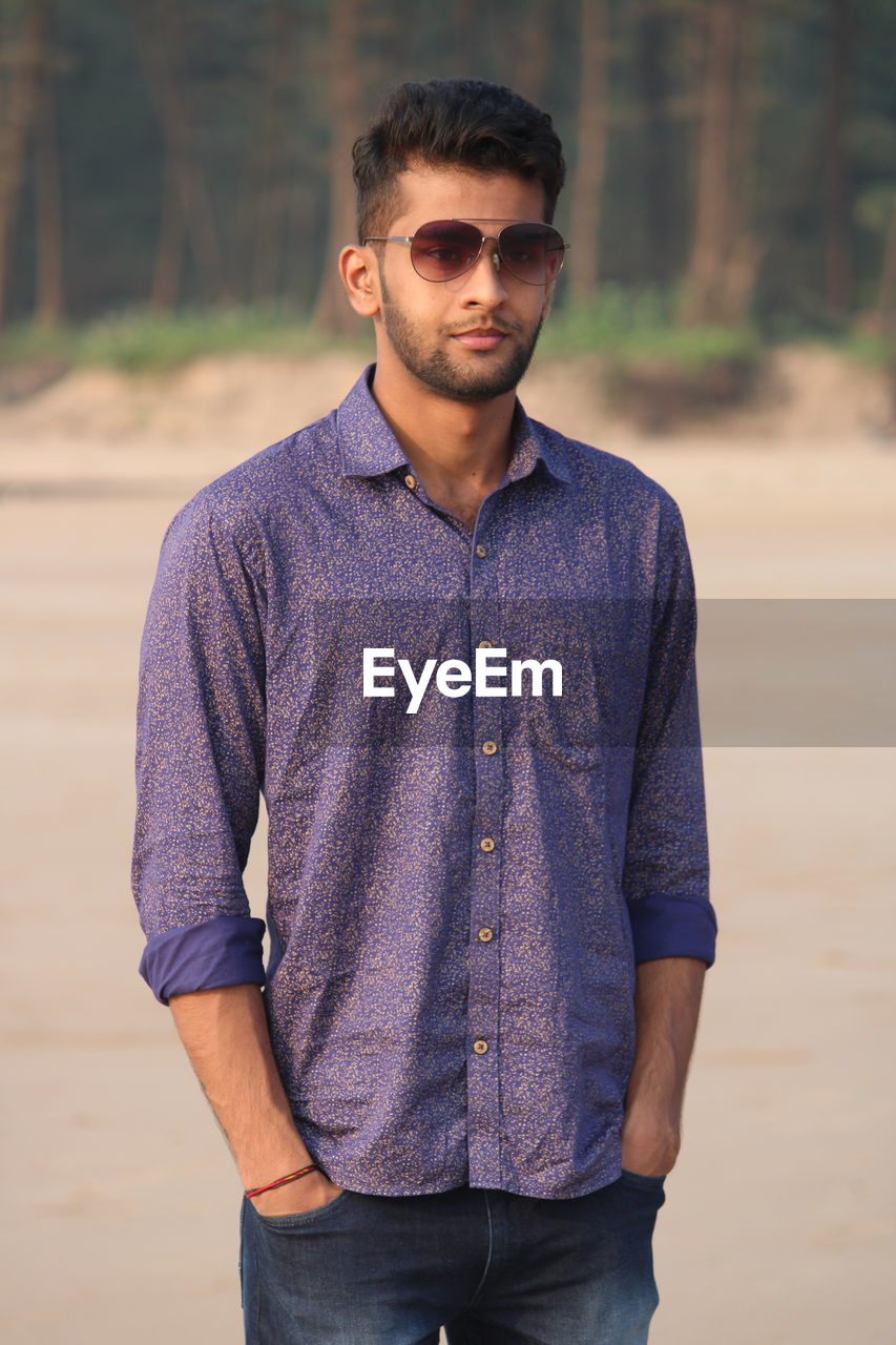 Portrait of young man wearing sunglasses standing outdoors