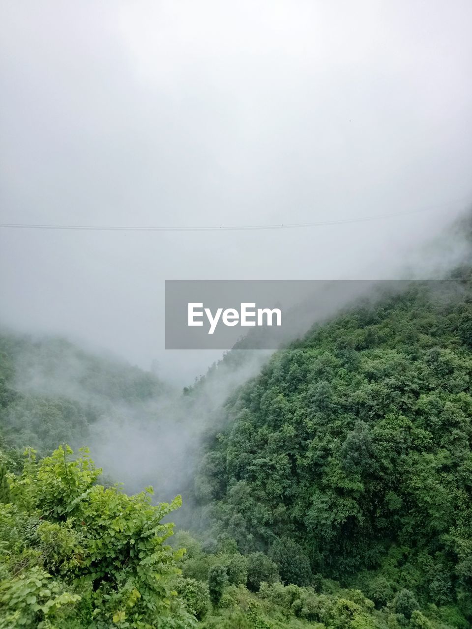 SCENIC VIEW OF MOUNTAINS IN FOGGY WEATHER AGAINST SKY