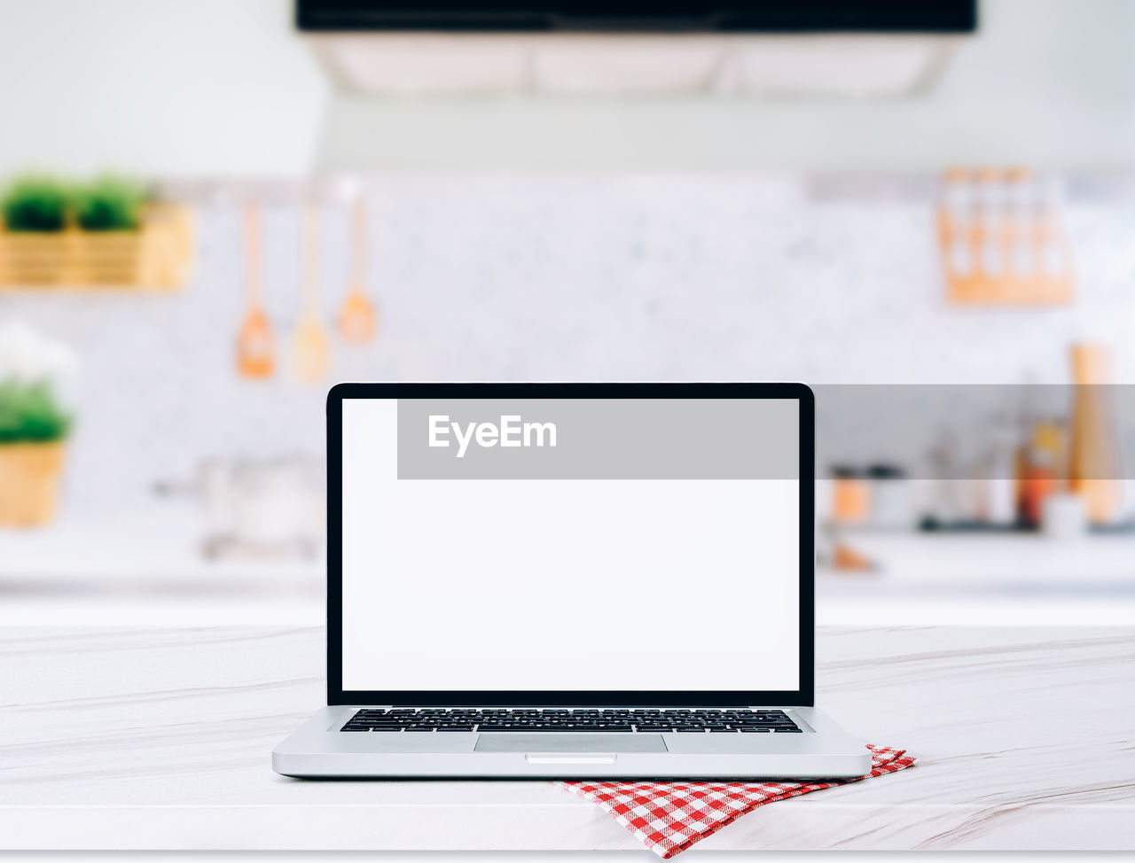 Modern computer,laptop with blank screen on wood table top on blurred kitchen background