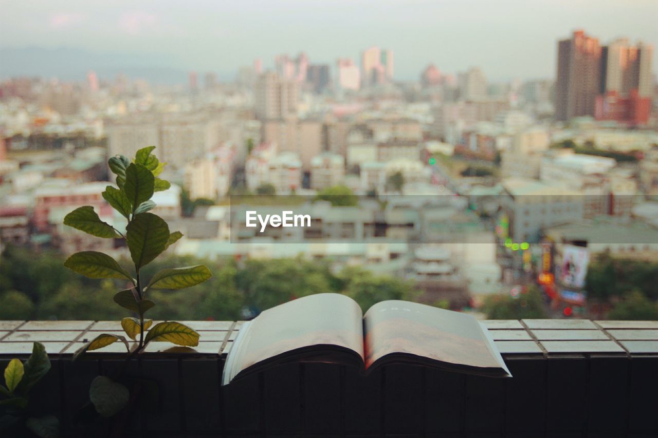 Open book on retaining wall of balcony against cityscape