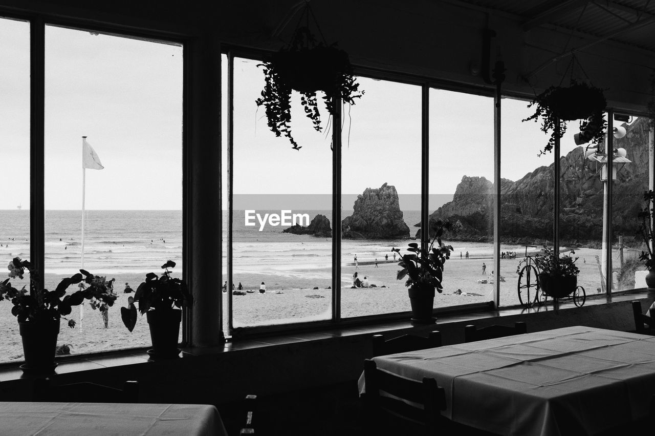 People at beach against sky seen through window