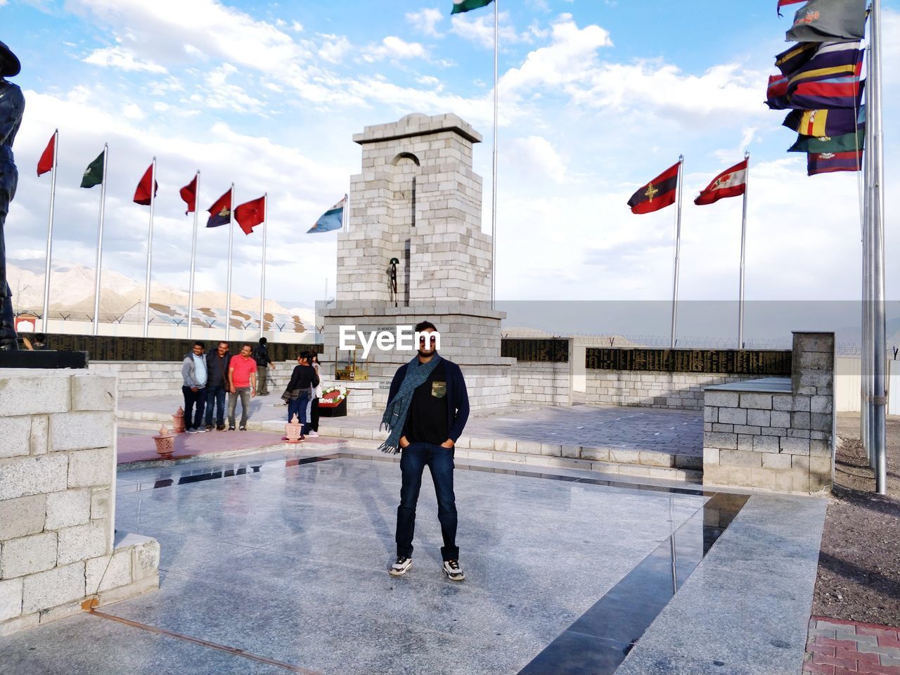 Full length portrait of man standing amidst flags against sky