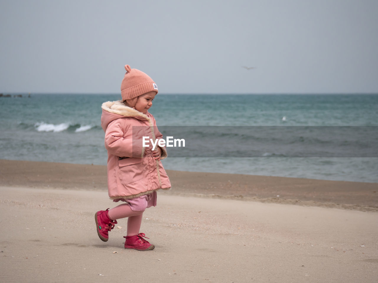 Side view of little girl walking on the beach