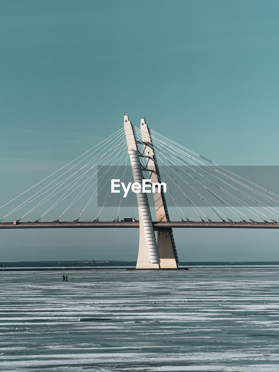 Suspension bridge over sea against clear sky