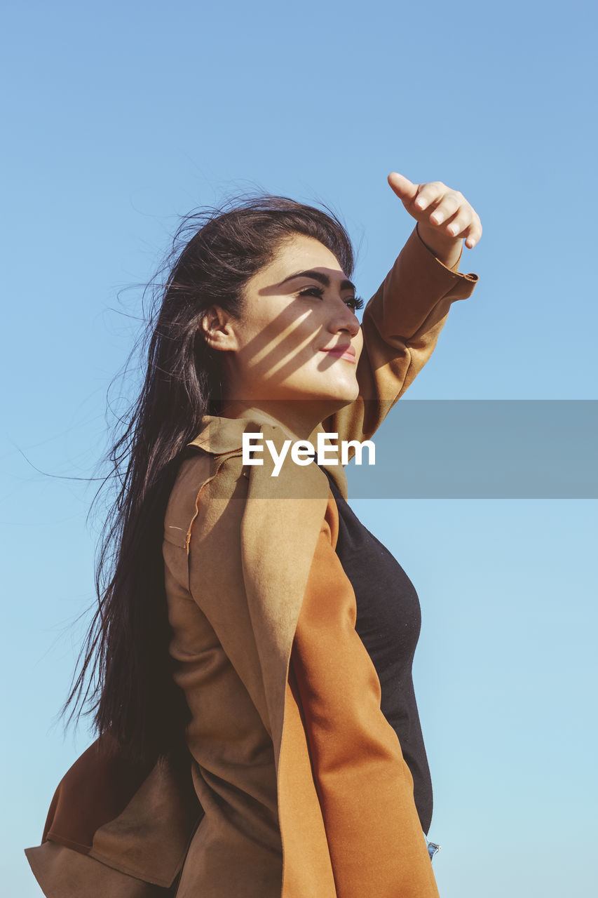 Low angle view of woman standing against clear sky