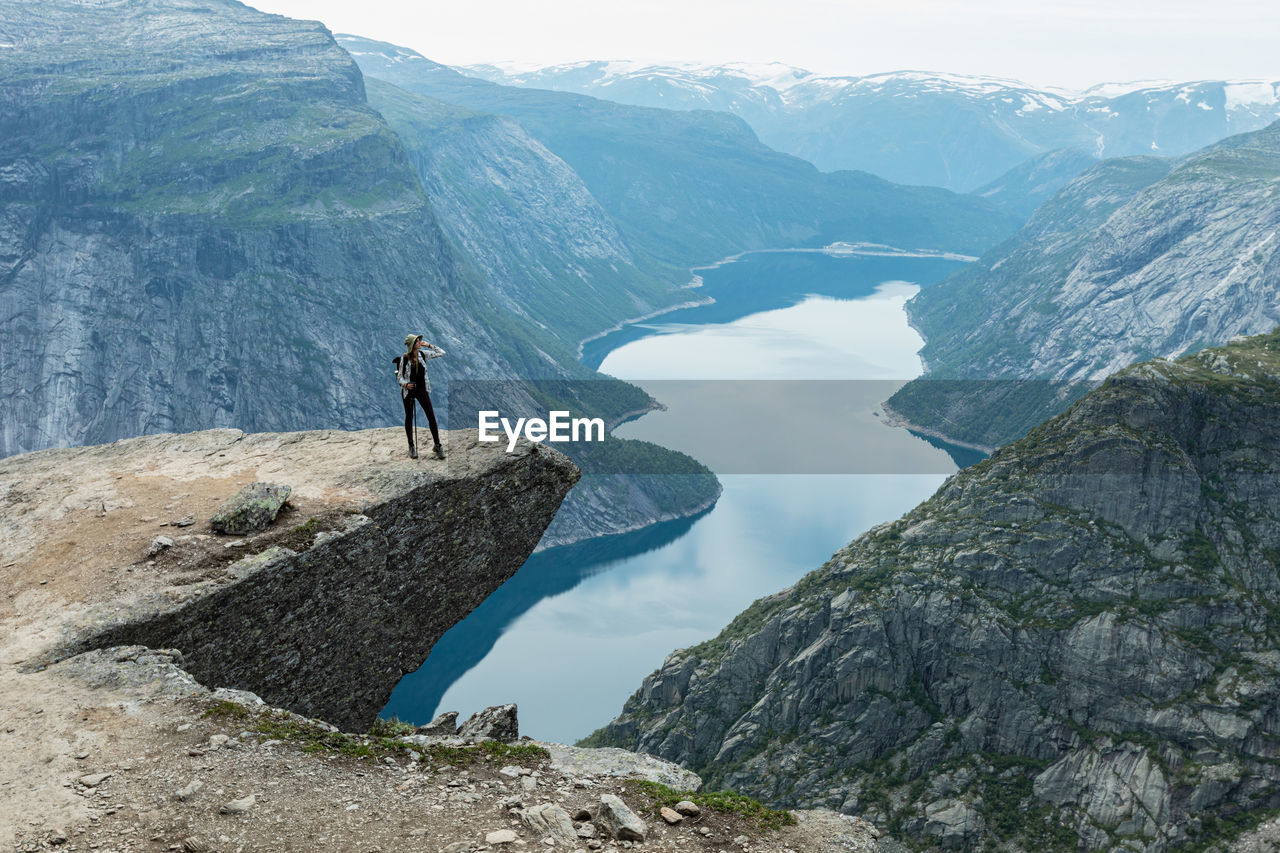 FULL LENGTH OF PERSON ON ROCKS AGAINST MOUNTAIN