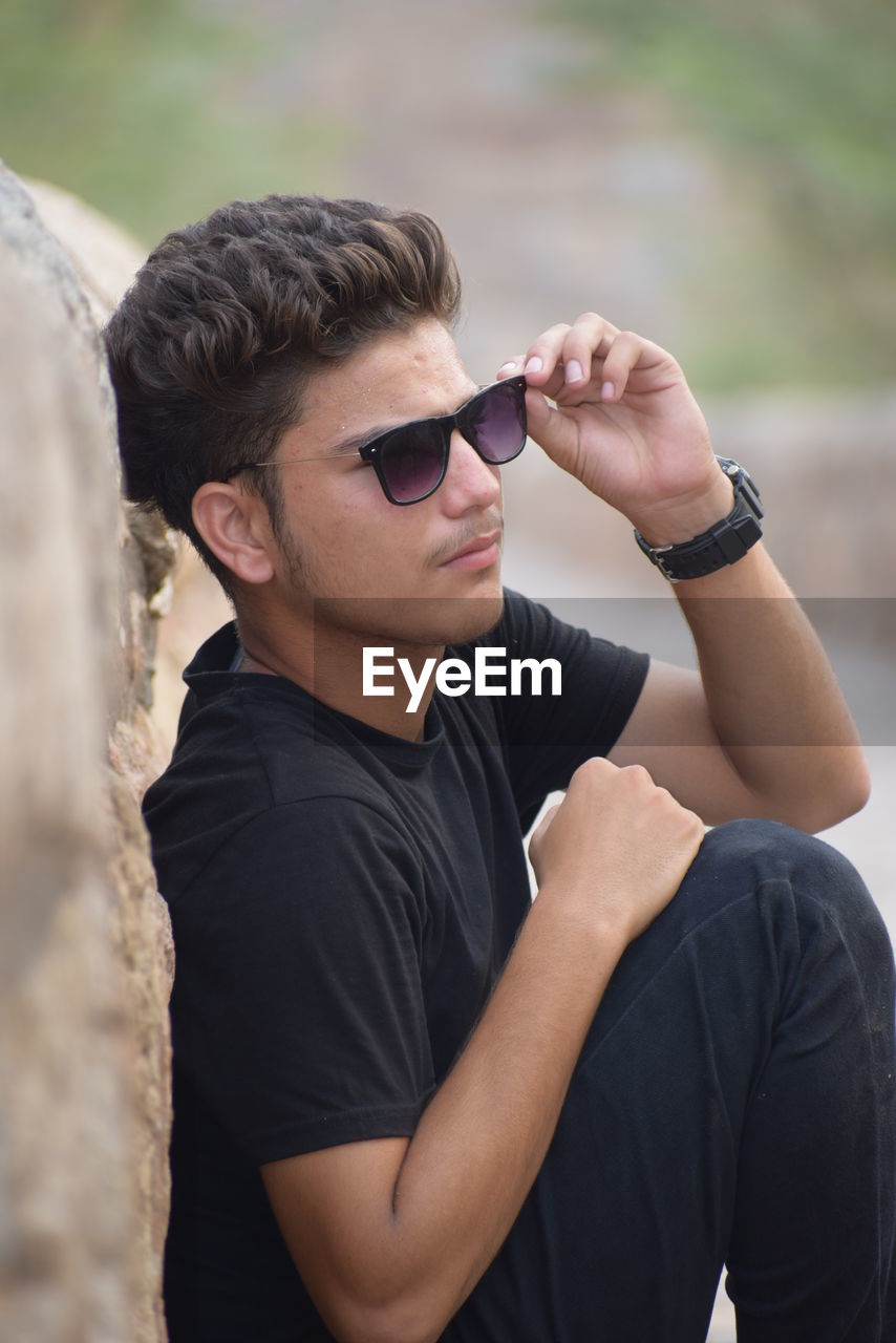 Young man wearing sunglasses against wall
