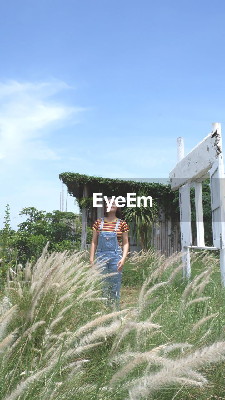 Portrait of woman standing by plants against sky