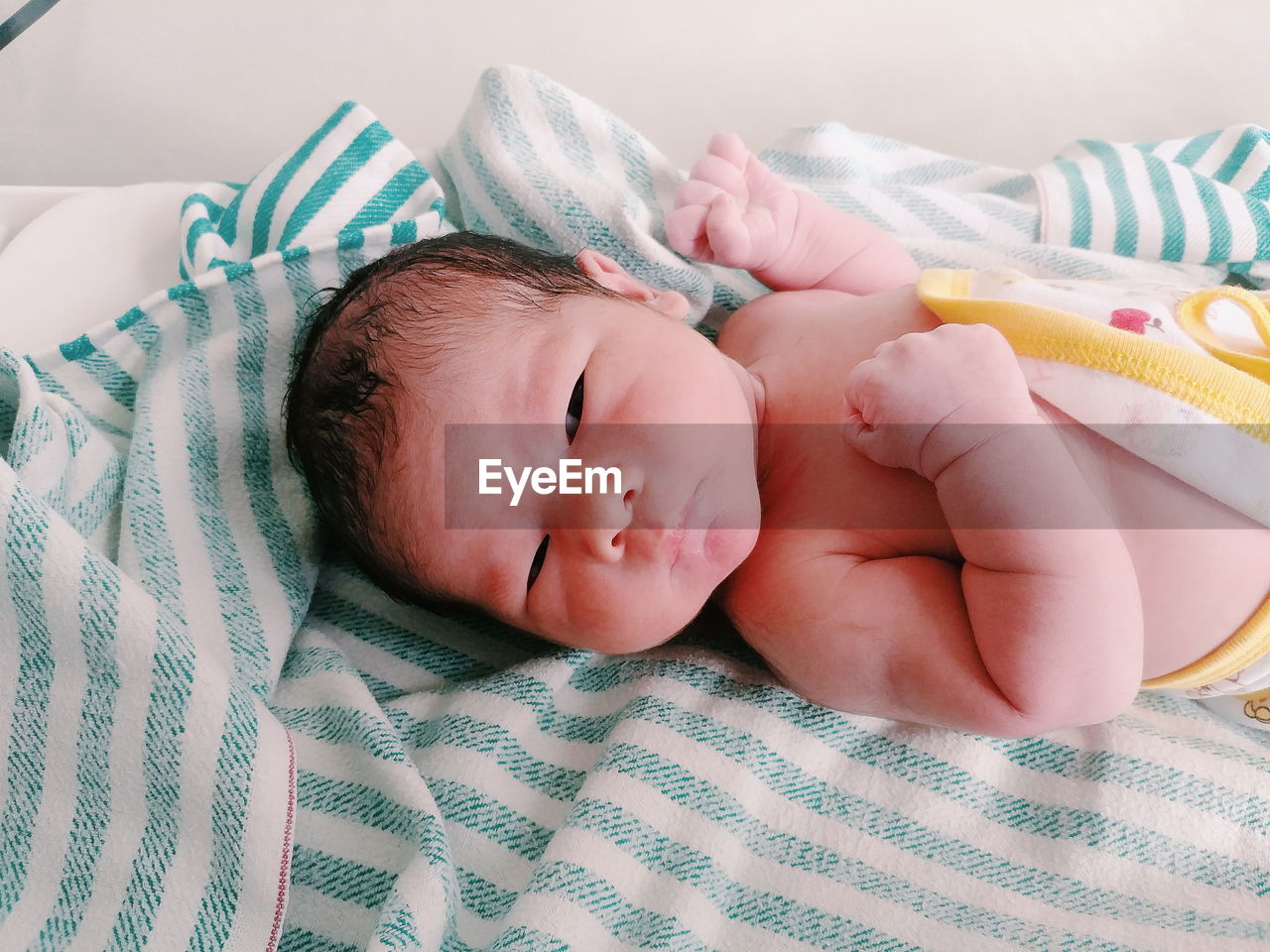 Close-up of cute baby girl lying on bed at home