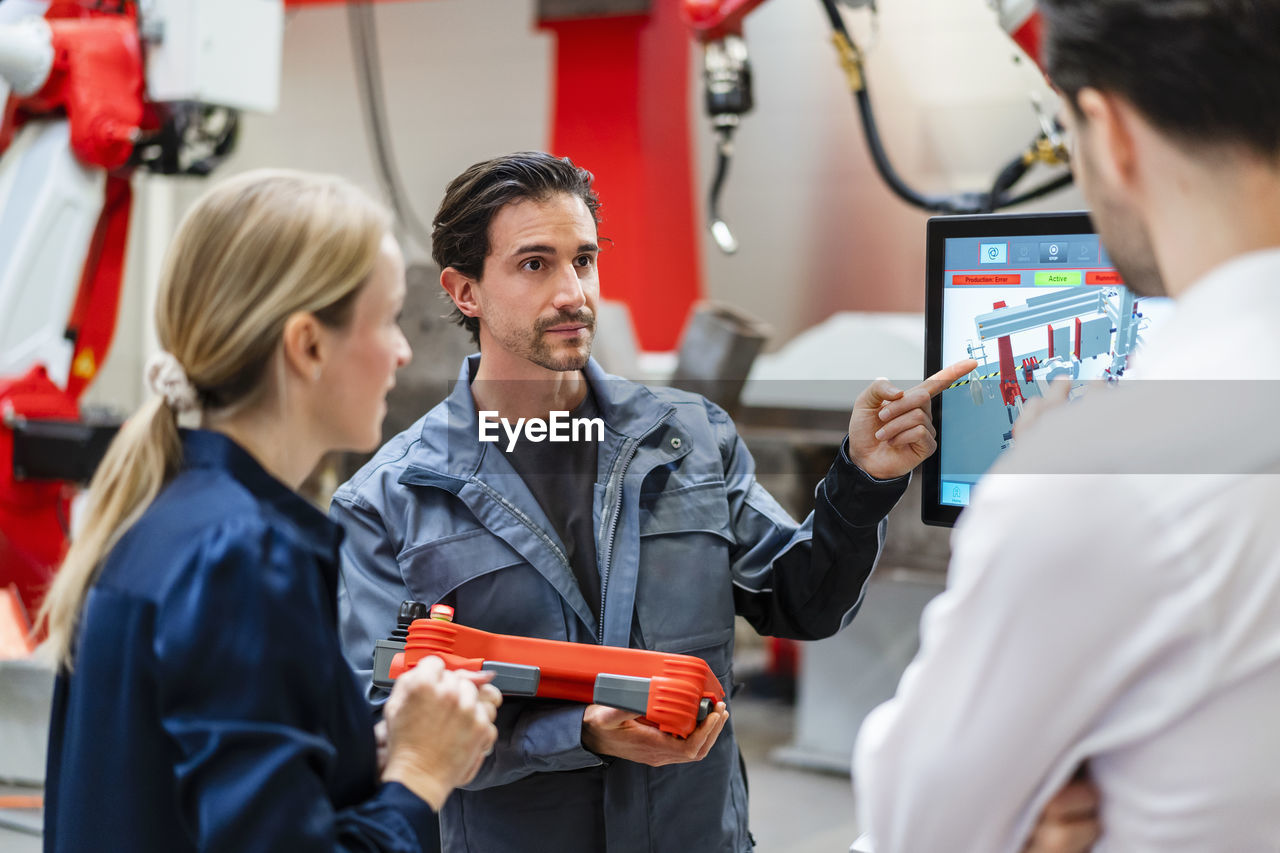 Engineer pointing and talking to colleagues in meeting at factory