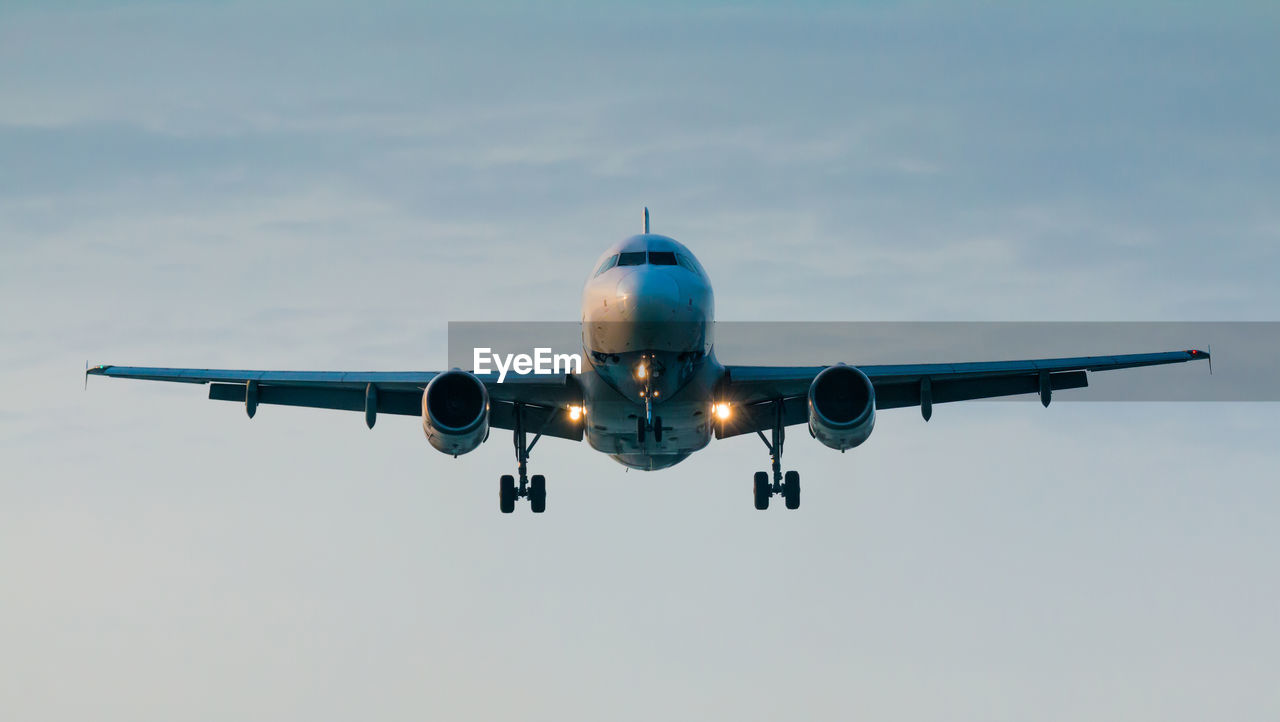 Low angle view of airplane flying against cloudy sky