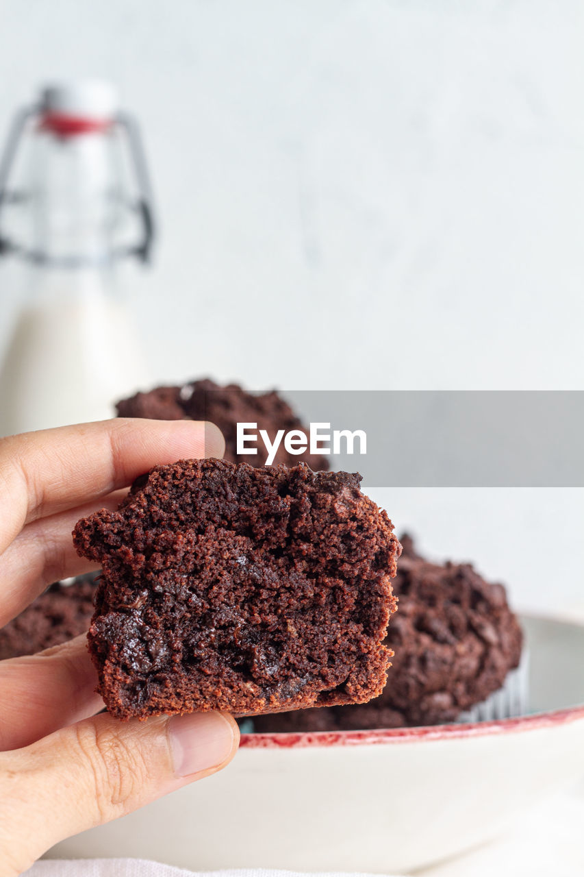 Crop anonymous person demonstrating half of yummy homemade chocolate muffin in light kitchen person