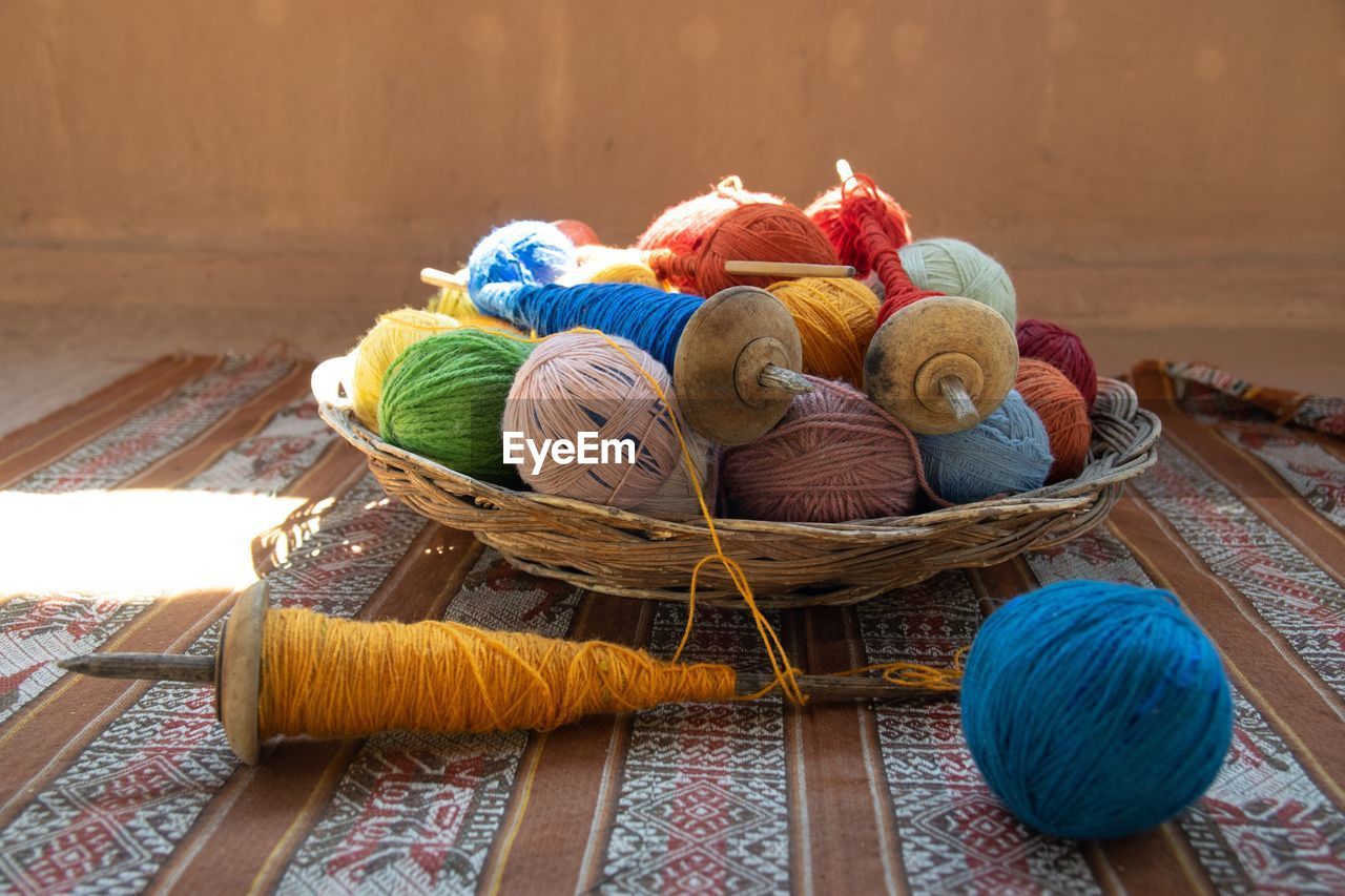 Colorful wool in basket on table