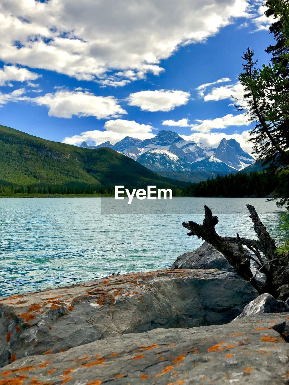 MAN JUMPING ON LAKE AGAINST MOUNTAINS