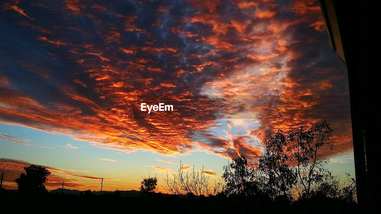 Low angle view of orange cloudy sky seen through window at dusk