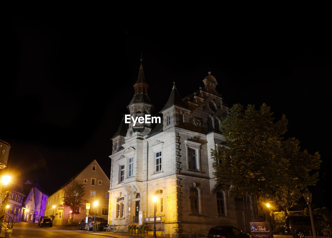 LOW ANGLE VIEW OF ILLUMINATED BUILDINGS AGAINST SKY AT NIGHT