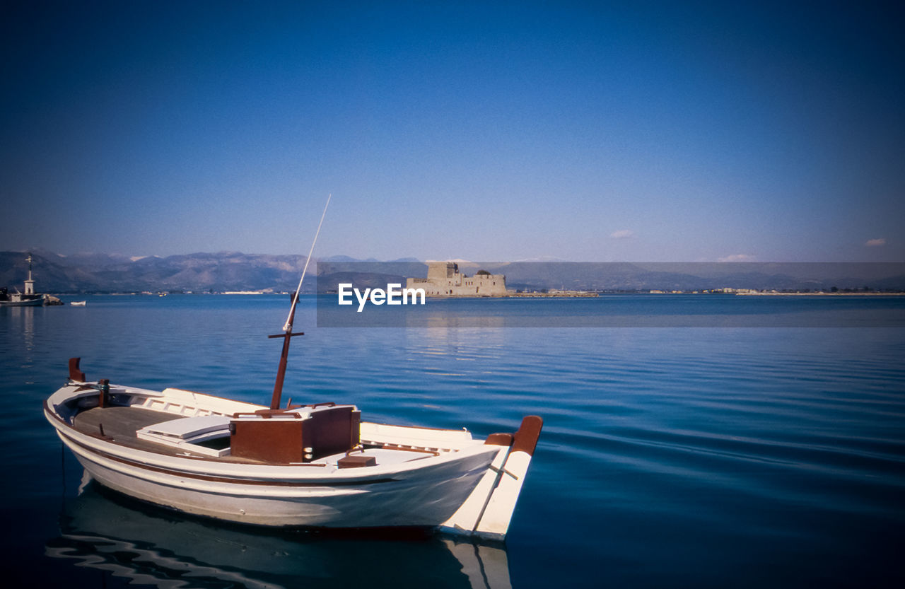 Boat in sea with bourtzi against clear sky