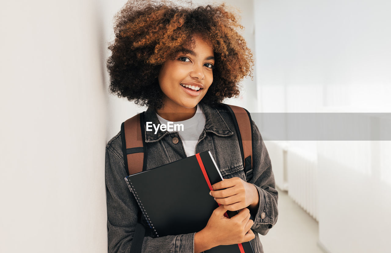 Afro student leaning on wall