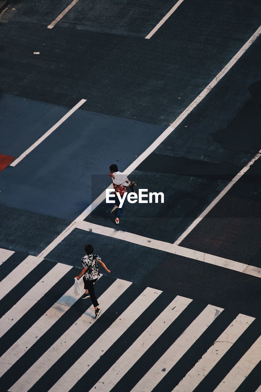 HIGH ANGLE VIEW OF PEOPLE CROSSING ROAD SIGN