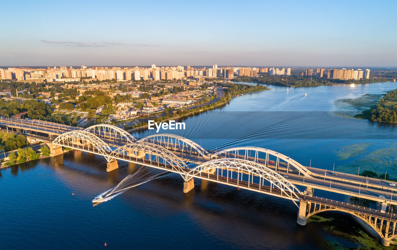 HIGH ANGLE VIEW OF BRIDGE OVER RIVER BY BUILDINGS